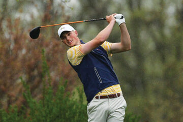 Man in a white cap swinging a golf club