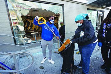 Community members clean up broken glass at McDonalds on 52nd Street in West Philadelphia, Sunday, June 1, 2020