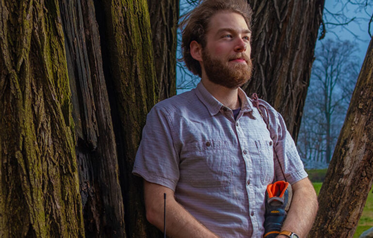 elliot leaning against a tree