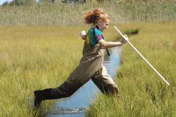 girl jumping over stream
