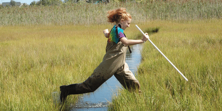 girl jumping over stream