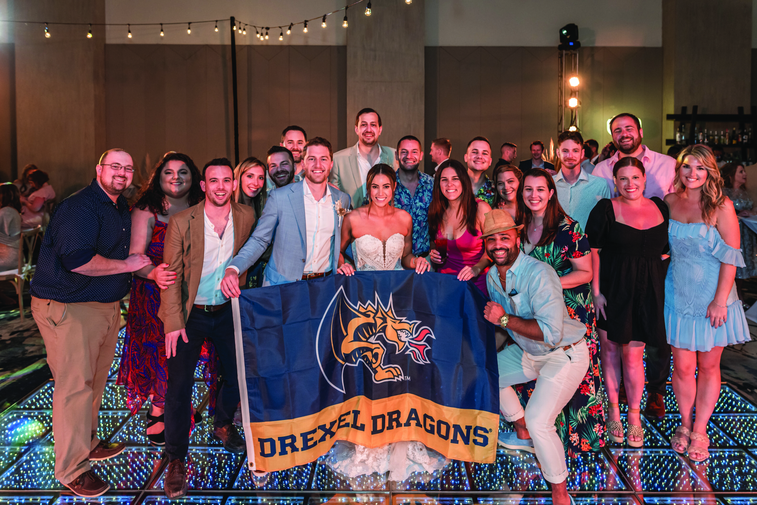 A group of guests hold up a Drexel Dragons flag at Nina Monzo and David Simons's wedding