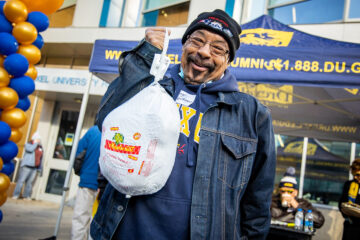 An Alumni Turkey Project volunteer holds up a turkey